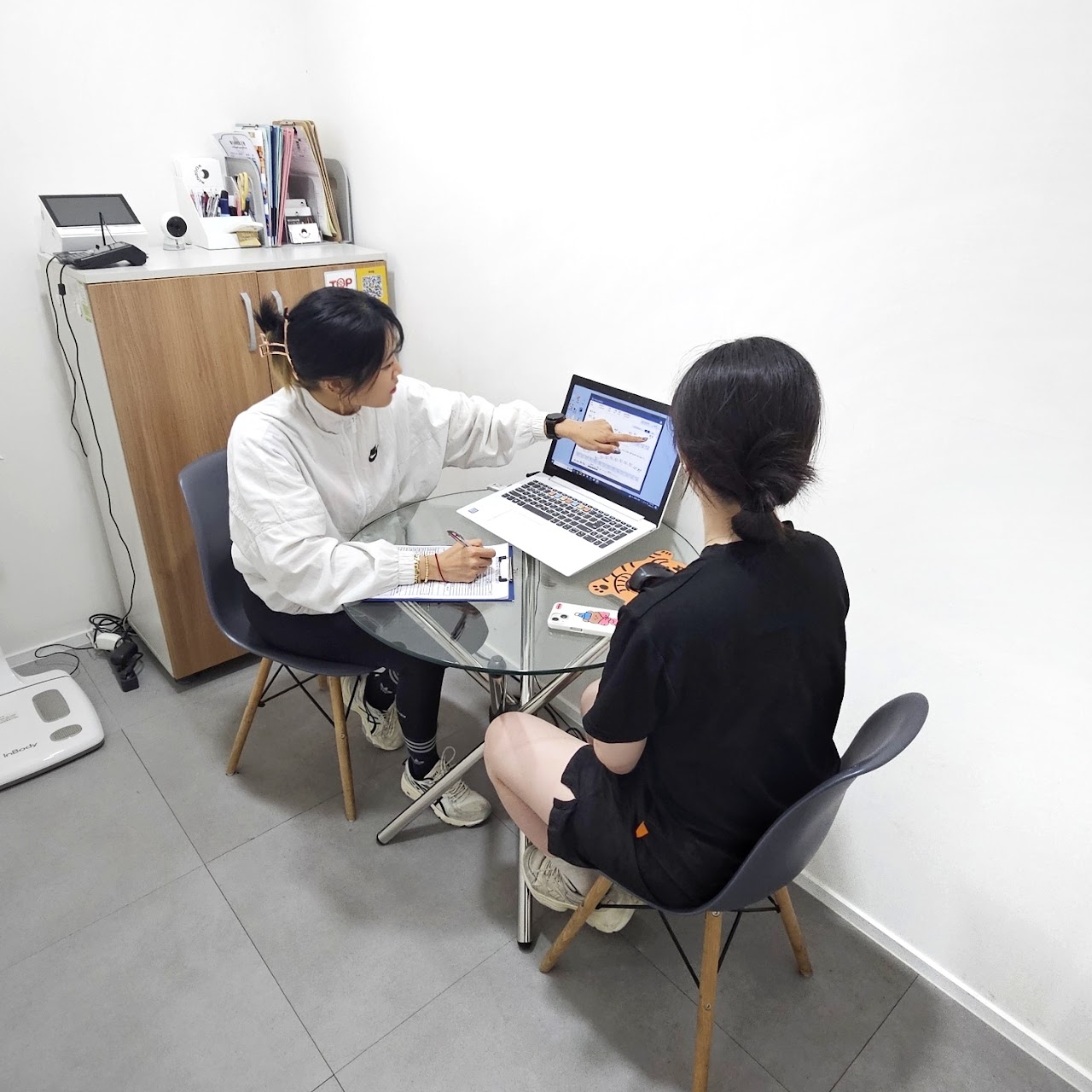 트레이너가 회원과 마주 앉아 노트북 화면을 보며 생활습관을 상담하는 모습